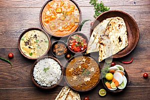 Indian lunch or dinner items like dal, paneer butter masala, roti, rice, salad photo