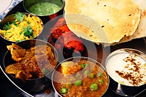 Assorted Indian food set in tray, tanduri chicken, naan bread, yoghurt, traditional curry, roti