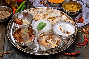 Assorted indian food set on wooden background. Dishes and appetisers of indeed cuisine, rice, lentils, paneer, samosa, spices.