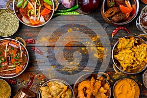 Assorted indian food set on wooden background. Dishes and appetisers of indeed cuisine, rice, lentils, paneer, samosa, spices. photo