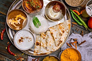 Assorted indian food set on wooden background. Dishes and appetisers of indeed cuisine, rice, lentils, paneer, samosa, spices, mas