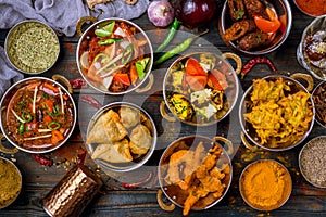 Assorted indian food set on wooden background. Dishes and appetisers of indeed cuisine, rice, lentils, paneer, samosa, spices, mas