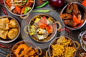 Assorted indian food set on wooden background. Dishes and appetisers of indeed cuisine, rice, lentils, paneer, samosa, spices, mas