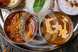 Assorted indian food set on wooden background. Dishes and appetisers of indeed cuisine, rice, lentils, paneer, samosa, spices, mas