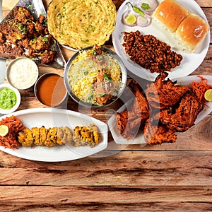 Assorted indian food on wooden background. Chicken Tikka, chicken briyani, tandoori chicken, , masala kulcha.. Dishes and