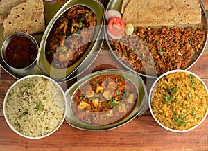 Assorted indian food on wooden background. Pepper chicken,paneer butter masala, jeera rice & chapati..Dishes and appetizers of