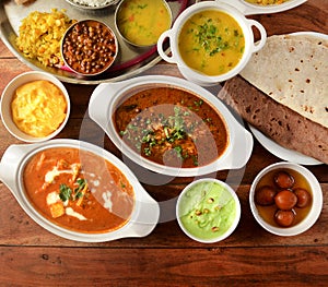 Assorted indian foods paneer butter masala,channa masala,roti and veg thali on wooden background. Dishes and appetizers of indian