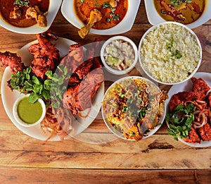 Assorted indian foods tandoori chicken,chicken biryani, chicken 65 and chicken masala on wooden background. Dishes and appetizers