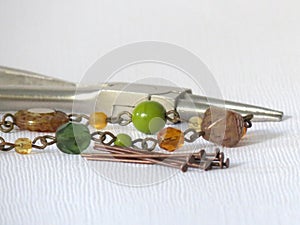 Assorted Jewelry Making Supplies on White Background - Piler, Glass Beads, Pins, Connectors. Handmade Craft Concept