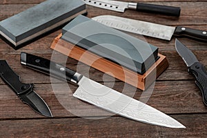 Assorted knives and whetstones on wooden table