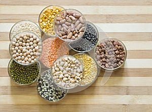 Assorted lentils and legumes in glass bowls, ona chopping board