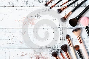 Assorted Makeup Brushes Arranged on a Distressed Wooden Surface With Paint Splatters