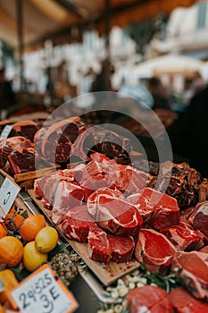 Assorted meat cuts on wooden tray in butcher shop with empty price tags for customization