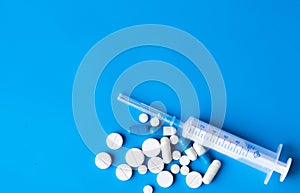 Assorted medical drugs and syringe on blue background, with copy space