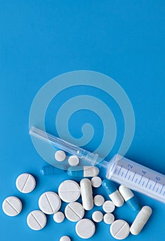 Assorted medical drugs and syringe on blue background, with copy space