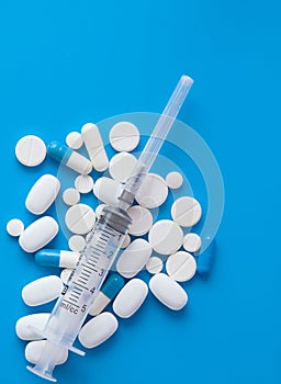 Assorted medical drugs and syringe on blue background, with copy space