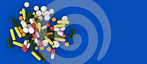 Assorted medical pills scattered on a floor with blue background. 3D rendering