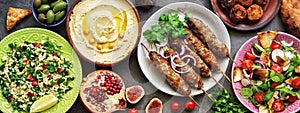 Assorted Middle Eastern and arabic dishes on a dark rustic background,border. Hummus,tabbouleh, salad Fattoush,pita,meat kebab,