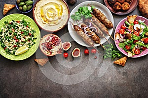 Assorted Middle Eastern and arabic dishes on a dark rustic background. Hummus,tabbouleh, salad Fattoush,pita,meat kebab,falafel,