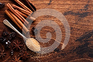 Assorted natural cinnamon, cane brown sugar, ground coffee, anise stars baking ingredients on a rustic brown background