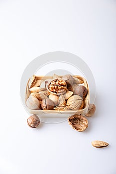 Assorted nuts in the shell on a white background: walnuts, pecans, almonds, macadamia. Nuts in a basket. Selective focus, close-up