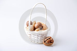 Assorted nuts in the shell on a white background: walnuts, pecans, almonds, macadamia. Nuts in a basket. Selective focus, close-up