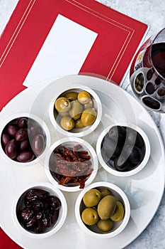 Assorted olives and sun-dried tomatoes with a glass of red wine. Place for text