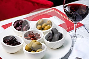 Assorted olives and sun-dried tomatoes with a glass of red wine. Place for text