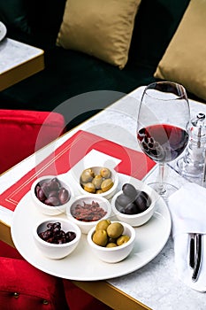 Assorted olives and sun-dried tomatoes with a glass of red wine. Place for text