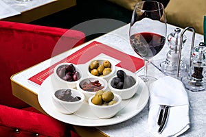 Assorted olives and sun-dried tomatoes with a glass of red wine. Place for text