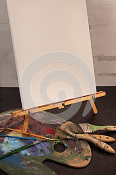 Assorted paintbrushes paint palette art white blank empty canvas easel