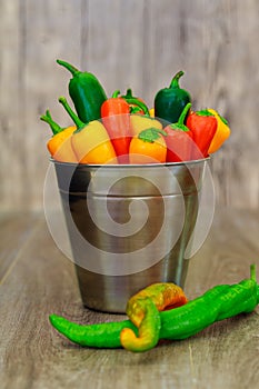 assorted peppers and chilies in a metal bucket with water droplets Vertical format