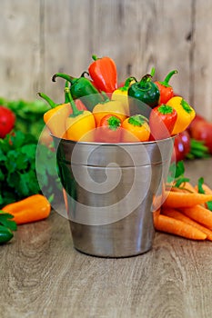 assorted peppers and chilies in a metal bucket with water droplets Vertical format