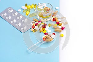 Assorted pharmaceutical medicine pills, tablets and capsules on blue and white background. Space for your text