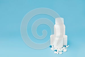 Assorted pharmaceutical medicine pills, tablets and capsules and bottle on blue background. Copy space for text