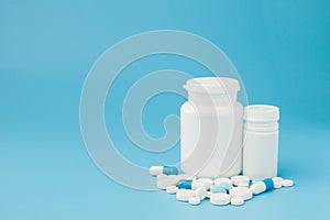 Assorted pharmaceutical medicine pills, tablets and capsules and bottle on blue background. Copy space for text