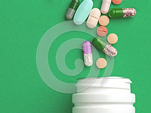 Assorted pharmaceutical medicine pills, tablets and capsules and bottle on green background. Copy space for text