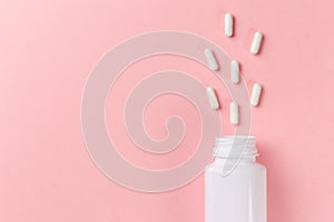 Assorted pharmaceutical medicine pills, tablets and capsules and bottle on pink background. Top view. Flat lay. Copy space