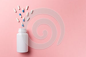 Assorted pharmaceutical medicine pills, tablets and capsules and bottle on pink background. Top view. Flat lay. Copy space