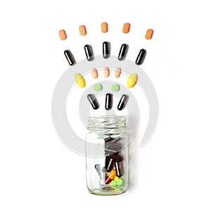 Assorted pharmaceutical medicine pills, tablets and capsules spilling out of pill bottle on white