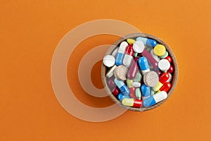 Assorted pharmaceutical medicine pills, tablets and capsules on wooden bowl. Pharmaceutical industry concept