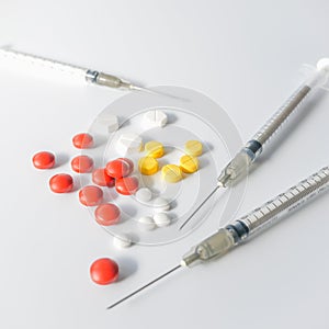 Assorted pharmaceutical medicine pills, tablets and syringe on white background