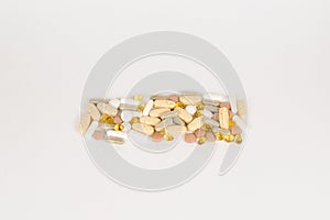 Assorted pharmaceutical various medicine pills, tablets and capsules of different colors on white background.. He