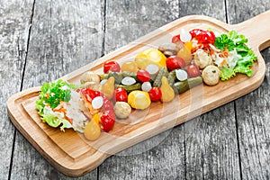 Assorted pickled vegetables - Sauerkraut cabbage, peppers, cucumbers, tomatoes, onions, mushrooms and herbs on cutting board