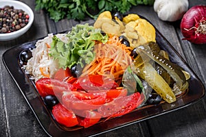 Assorted pickled vegetables - Sauerkraut cabbage, watermelon, peppers, cucumbers, tomatoes and herbs on light wooden background.