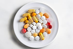 Assorted pills are in a white plate. Different tablets and capsules. Copy space