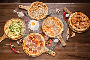 Assorted pizza with seafood and cheese, four cheeses, pepperoni, meat, margarita on a wooden stand with spices