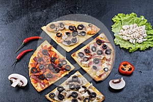 Assorted pizza slices. Margherita, pepperoni, four cheese pizza. Top view. Different types of pizza on the textured old