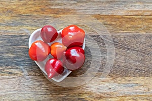 Assorted red chili peppers and spicy mini stacked in a plate heart top view