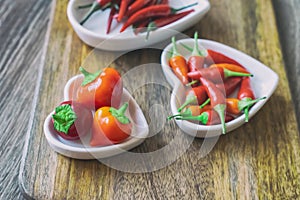 Assorted red fresh hot peppers on a background of chili in white plates selective focus